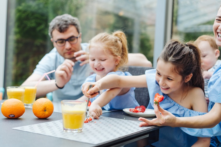 Preschoolers eating fruit in company of an adult