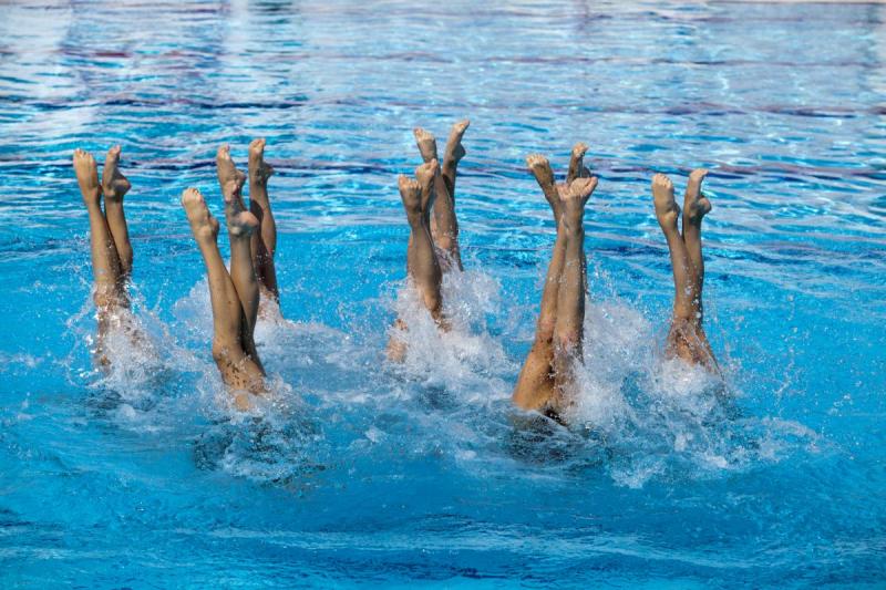 Synchronized swimmer's legs above the water surface of a swimming pool